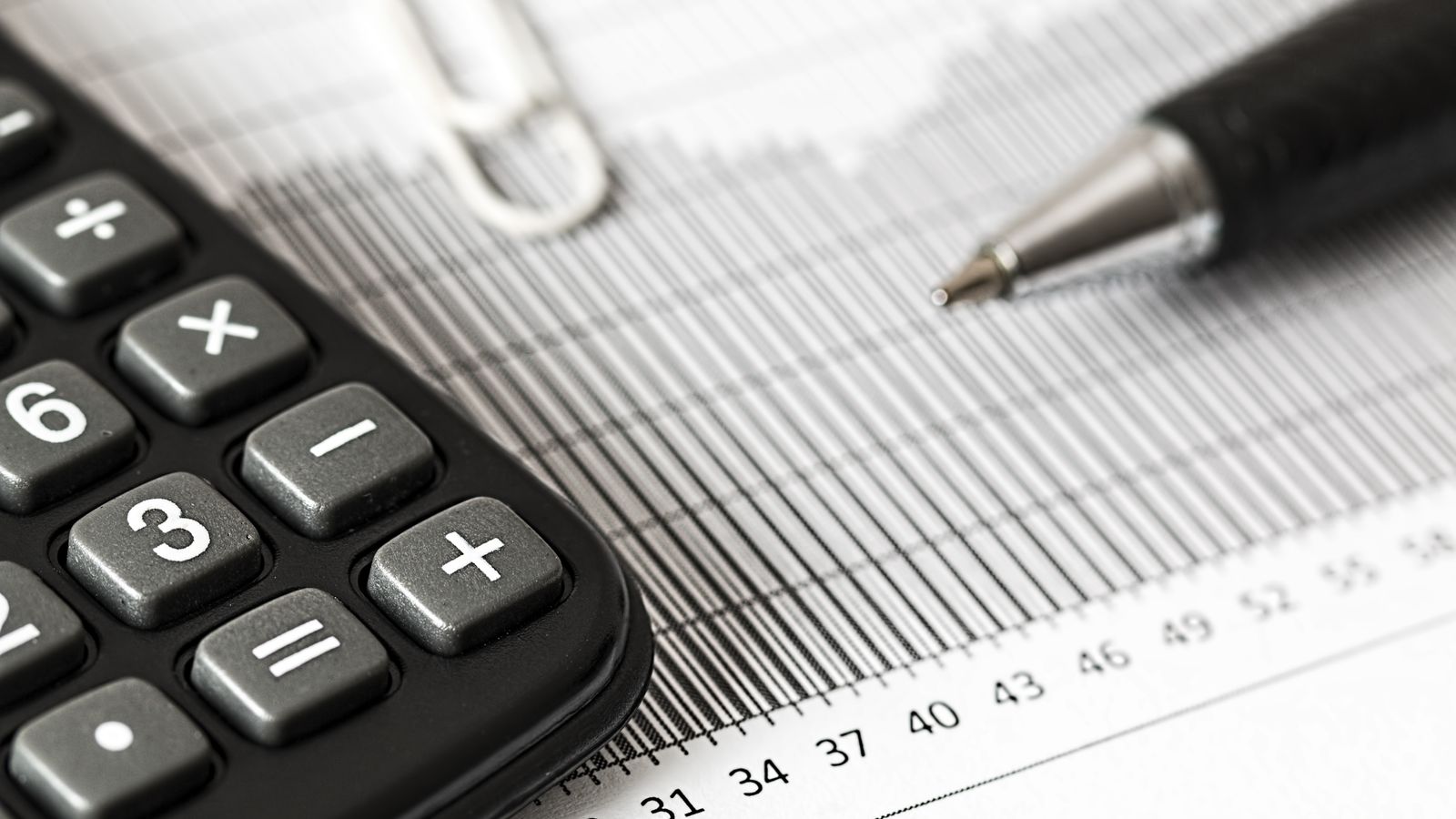 Calculator and pen resting on a financial chart
