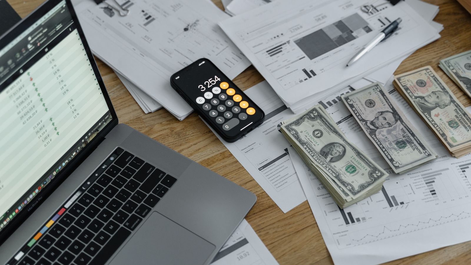 Calculator, cash, and financial reports on a desk